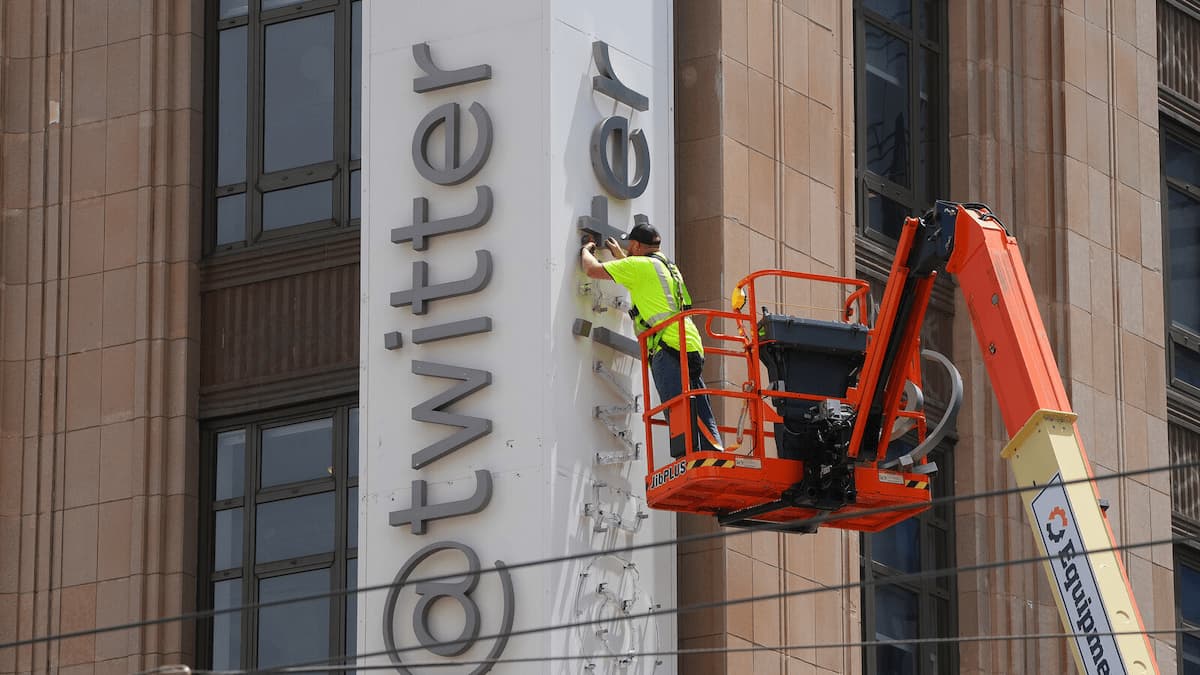 A photo of a construction worker taking down the Twitter logo on the side of the company's SF headquarters.